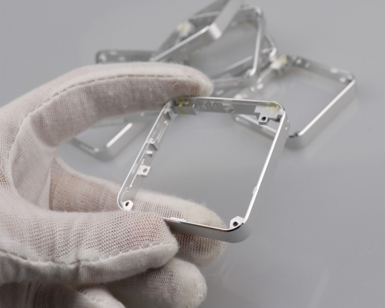 Gloved hand holding a precision-machined metal enclosure frame